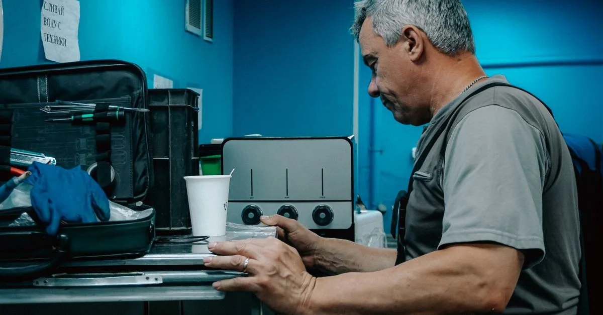 Un technicien travaille sur une machine dans un environnement industriel, concentré sur le réglage des commandes.