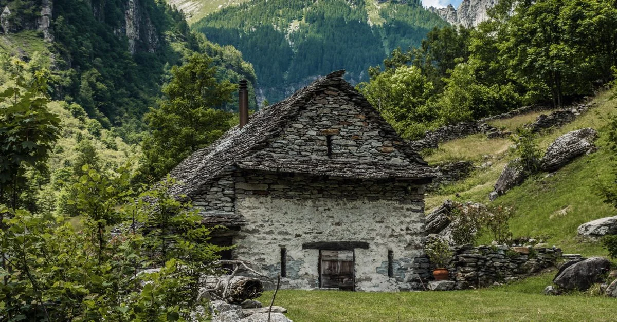 Charmante maison en pierre nichée dans une végétation luxuriante et un paysage montagneux.