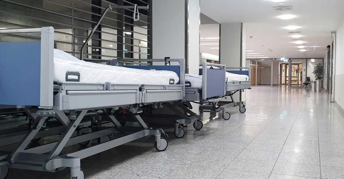 Couloir d'hôpital silencieux avec des lits médicaux vides soigneusement rangés sous des lumières brillantes.